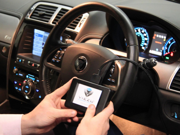 Hands holding Home ECU Remapping Device in front seat of a car steering wheel